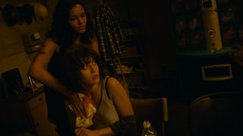 Movie still from “Cloverfield” (2008), directed by Matt Reeves – Two women in a dark room one of them is holding a tissue; Medium shot, High angle