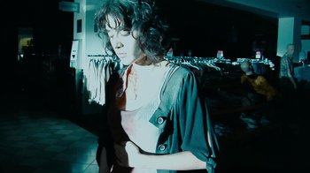 Movie still from “Cloverfield” (2008), directed by Matt Reeves – A woman with curly brown hair standing in a store; Medium shot, Low angle