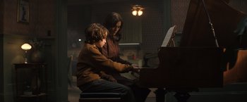 Movie still from “Cobweb” (2023), directed by Samuel Bodin – A woman and a boy are playing a piano together; Medium shot, High angle