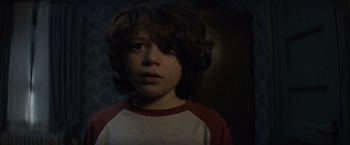 Movie still from “Cobweb” (2023), directed by Samuel Bodin – A young boy is looking into the camera; Close Up shot, Over the shoulder angle