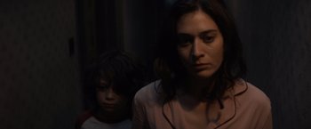 Movie still from “Cobweb” (2023), directed by Samuel Bodin – A woman standing next to a child in a dark room; Close Up shot, Low angle