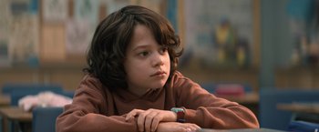 Movie still from “Cobweb” (2023), directed by Samuel Bodin – A young boy sitting at a table with his hand on his chin; Close Up shot, Low angle