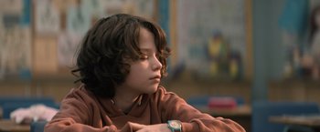 Movie still from “Cobweb” (2023), directed by Samuel Bodin – A young boy sitting down with his arms folded on his chest; Close Up shot, Low angle