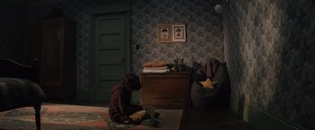 Movie still from “Cobweb” (2023), directed by Samuel Bodin – A child sitting on the floor in a room; Wide shot, High angle