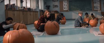 Movie still from “Cobweb” (2023), directed by Samuel Bodin – A group of people sitting on the ground with pumpkins; Wide shot, High angle