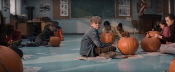 Movie still from “Cobweb” (2023), directed by Samuel Bodin – A boy sitting on the floor next to pumpkins; Wide shot, High angle