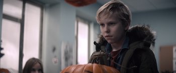 Movie still from “Cobweb” (2023), directed by Samuel Bodin – A young boy standing in front of a pumpkin; Close Up shot, Over the shoulder angle