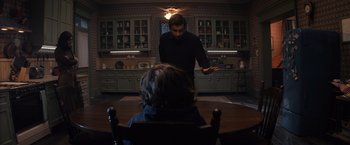 Movie still from “Cobweb” (2023), directed by Samuel Bodin – A man standing in front of a woman sitting at a table; Medium shot, Over the shoulder angle