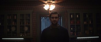 Movie still from “Cobweb” (2023), directed by Samuel Bodin – A man standing in front of a ceiling fan in a room; Medium shot, Low angle