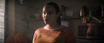 Movie still from “Cobweb” (2023), directed by Samuel Bodin – A woman wearing a sweater is looking at the camera; Close Up shot, Over the shoulder angle