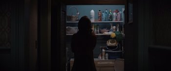 Movie still from “Cobweb” (2023), directed by Samuel Bodin – A woman standing in front of a shelf in a kitchen; Medium shot, Over the shoulder angle