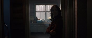 Movie still from “Cobweb” (2023), directed by Samuel Bodin – A woman standing in front of a window in a kitchen; Medium shot, Over the shoulder angle