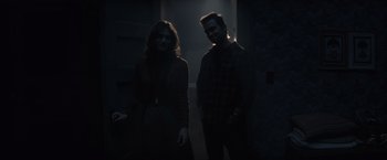 Movie still from “Cobweb” (2023), directed by Samuel Bodin – A man and a woman standing next to each other in the dark; Medium shot, Over the shoulder angle