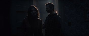 Movie still from “Cobweb” (2023), directed by Samuel Bodin – A man and a woman standing next to each other in the dark; Medium shot, Over the shoulder angle