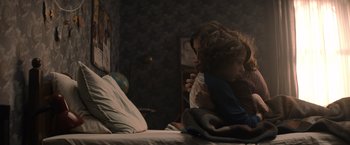 Movie still from “Cobweb” (2023), directed by Samuel Bodin – A woman and a child sitting on a bed in a room; Medium shot, Over the shoulder angle