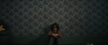 Movie still from “Cobweb” (2023), directed by Samuel Bodin – A boy sitting on the ground in front of a wall; Medium shot, High angle