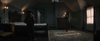 Movie still from “Cobweb” (2023), directed by Samuel Bodin – A woman standing in a room next to a bed; Wide shot, Over the shoulder angle