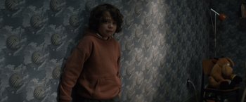 Movie still from “Cobweb” (2023), directed by Samuel Bodin – A young boy standing in front of a wall; Medium shot, High angle
