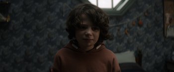 Movie still from “Cobweb” (2023), directed by Samuel Bodin – A young boy wearing a brown hoodie and looking at the camera; Close Up shot, Over the shoulder angle