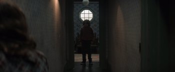 Movie still from “Cobweb” (2023), directed by Samuel Bodin – A person standing in a hallway with a ball hanging from the ceiling; Wide shot, Low angle