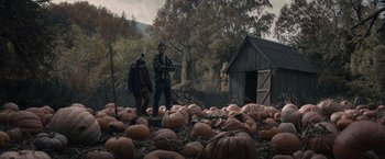 Movie still from “Cobweb” (2023), directed by Samuel Bodin – Two men standing next to a pile of pumpkins in a field; Wide shot, High angle
