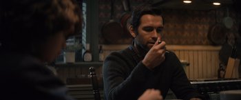 Movie still from “Cobweb” (2023), directed by Samuel Bodin – A man sitting at a table with a cigarette in his mouth; Close Up shot, Over the shoulder angle