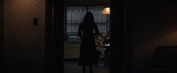 Movie still from “Cobweb” (2023), directed by Samuel Bodin – A woman standing in front of a window in a kitchen; Wide shot, Over the shoulder angle