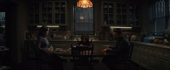 Movie still from “Cobweb” (2023), directed by Samuel Bodin – A group of people sitting around a table in a kitchen; Wide shot, Over the shoulder angle