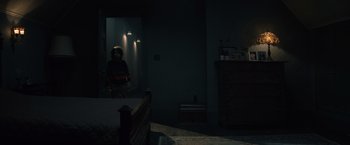 Movie still from “Cobweb” (2023), directed by Samuel Bodin – A person standing in a dark room in front of a mirror; Wide shot, High angle