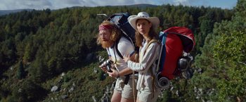 Movie still from “Cocaine Bear” (2023), directed by Elizabeth Banks – A man and a woman standing next to each other on top of a mountain; Wide shot, Low angle