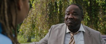 Movie still from “Cocaine Bear” (2023), directed by Elizabeth Banks – An older black man in a suit and tie; Close Up shot, Over the shoulder angle