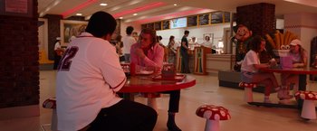 Movie still from “Cocaine Bear” (2023), directed by Elizabeth Banks – Two people are sitting at a table in a restaurant; Wide shot, Over the shoulder angle