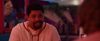 Movie still from “Cocaine Bear” (2023), directed by Elizabeth Banks – A person with a beard wearing a necklace; Close Up shot, Over the shoulder angle