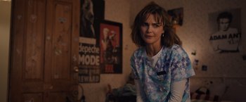 Movie still from “Cocaine Bear” (2023), directed by Elizabeth Banks – A woman in a room with a poster on the wall; Close Up shot, Over the shoulder angle