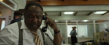 Movie still from “Cocaine Bear” (2023), directed by Elizabeth Banks – An older man talking on a phone while sitting in a room; Close Up shot, Low angle