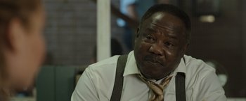 Movie still from “Cocaine Bear” (2023), directed by Elizabeth Banks – A man in a white shirt and a brown tie; Close Up shot, Over the shoulder angle