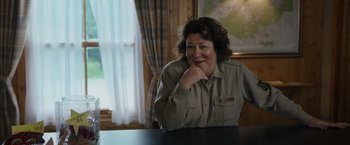 Movie still from “Cocaine Bear” (2023), directed by Elizabeth Banks – A woman sitting at a table in front of a map; Close Up shot, Over the shoulder angle