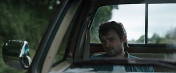 Movie still from “Cocaine Bear” (2023), directed by Elizabeth Banks – A man sitting in the back seat of a car looking out the window; Close Up shot, Over the shoulder angle
