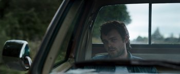 Movie still from “Cocaine Bear” (2023), directed by Elizabeth Banks – A man sitting in the passenger seat of a car looking out the window; Close Up shot, Over the shoulder angle