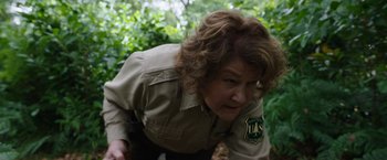 Movie still from “Cocaine Bear” (2023), directed by Elizabeth Banks – A woman in a uniform is crouching down; Close Up shot, Over the shoulder angle