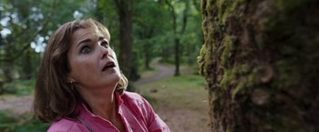 Movie still from “Cocaine Bear” (2023), directed by Elizabeth Banks – A woman in a pink shirt looking up at a tree; Close Up shot, Low angle