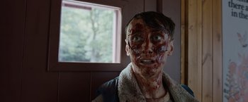 Movie still from “Cocaine Bear” (2023), directed by Elizabeth Banks – A young man with fake blood on his face; Close Up shot, Low angle