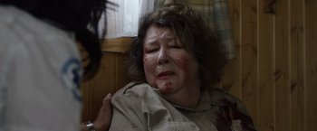 Movie still from “Cocaine Bear” (2023), directed by Elizabeth Banks – An older woman with bruises on her face; Close Up shot, Over the shoulder angle