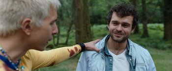 Movie still from “Cocaine Bear” (2023), directed by Elizabeth Banks – A man with a broken arm being helped by another man; Close Up shot, Over the shoulder angle