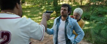 Movie still from “Cocaine Bear” (2023), directed by Elizabeth Banks – A man holding a gun up to another man's face; Medium shot, Over the shoulder angle