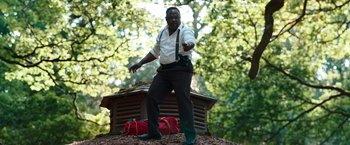 Movie still from “Cocaine Bear” (2023), directed by Elizabeth Banks – A man standing on top of a pile of leaves; Wide shot, Low angle