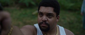 Movie still from “Cocaine Bear” (2023), directed by Elizabeth Banks – A person with a beard wearing a necklace; Close Up shot, High angle