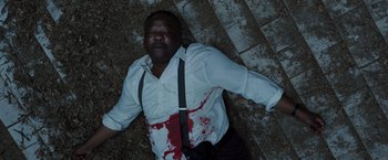 Movie still from “Cocaine Bear” (2023), directed by Elizabeth Banks – A man in a white shirt with blood on his chest; Medium shot, Overhead angle