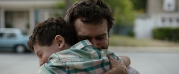 Movie still from “Cocaine Bear” (2023), directed by Elizabeth Banks – A man holding a child in his arms; Close Up shot, Over the shoulder angle
