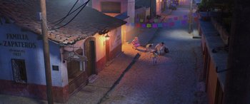 Movie still from “Coco” (2017), directed by Adrian Molina – People sitting on the side of a street at night; Extreme Wide shot, High angle